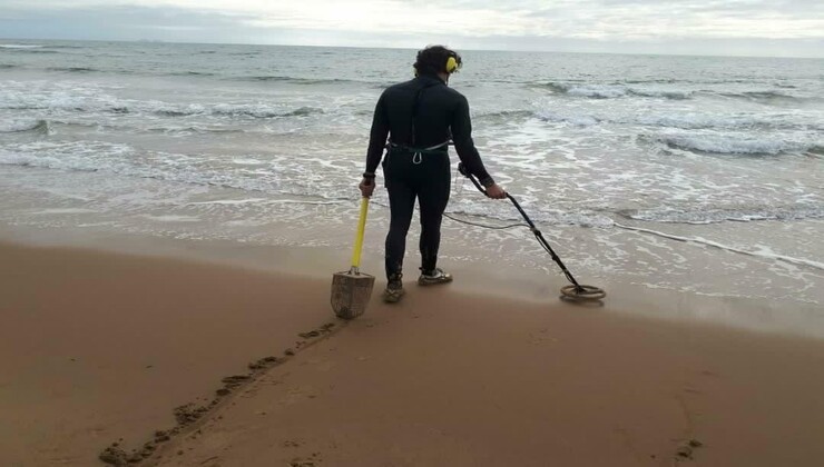Uomo con metal detector in spiaggia