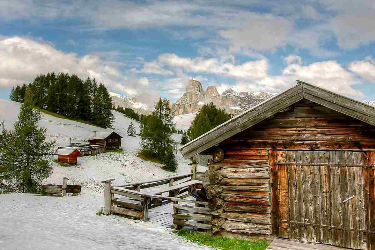 Montagne innevate con casa di legno